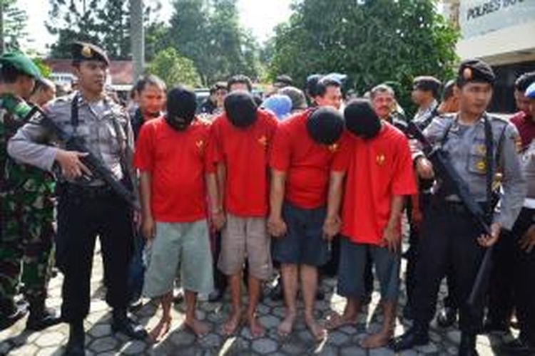 Petugas polisi dari Polres Bogor menjaga ketat pelaku pengedar narkoba, saat pemusnahan barang bukti narkoba di Lapangan Polres Bogor, Rabu (19/11/2014). K97-14