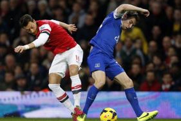 Gelandang Arsenal, Mesut Oezil (kiri) berebut bola dengan bek Everton, Seamas Coleman, dalam lanjutan Premier League di Stadion Emirates, Minggu (8/12/2013). 