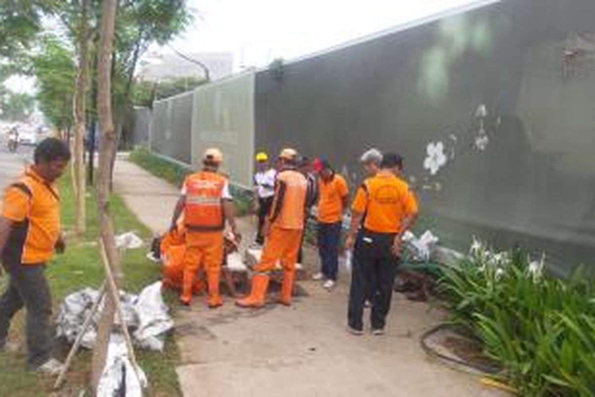 Sejumlah Petugas Penanganan Prasarana dan Sarana Umum (PPSU) Kelurahan Kedoya Utara saat membersihkan saluran air yang ada di depan proyek pembangunan Wang Residence, Kedoya, Kebon Jeruk, Jakarta Barat, Minggu (27/12/2015). Warga sekitar menyebut proyek pembangunan apartemen tersebut telah memutus saluran air yang menjadi jalur pembuangan dari perumahan ke Kali Sekretaris.