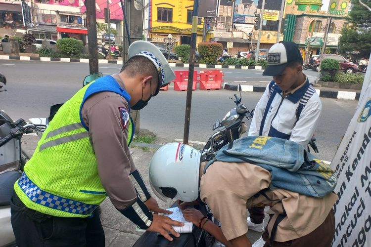 Pengendara motor yang tak menggunakan helm saat berkendara di Jalan Margonda Raya, Depok, terkena tilang manual pada Rabu (17/5/2023).