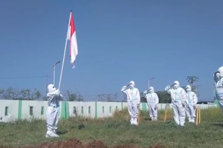 UPACARA BENDERA—Relawan tim pemakaman jenazah pasien covid-19 menggelar upacara bendera untuk memperingati HUT RI Ke-76 di halaman tempat pemakaman umum Pagu Indah, Kelurahan Manisrejo, Kecamatan Taman, Kota Madiun, Jawa Timur, Minggu (15/8/2021).