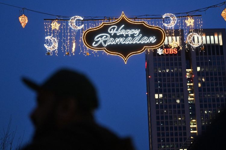 Orang-orang mengambil gambar dengan ponsel mereka, karena untuk pertama kalinya di Jerman, pada tanggal 10 Maret 2024 di Frankfurt, sebuah jalan diterangi ornamen-ornamen khas selama bulan Ramadhan. Puasa di siang hari pada bulan Ramadhan adalah salah satu dari lima rukun Islam. Umat Islam yang taat menahan diri dari makan dan minum dari fajar hingga senja, dan secara tradisional berkumpul dengan keluarga dan teman untuk berbuka puasa di malam hari. Bulan Ramadan juga merupakan waktu untuk berdoa, dengan umat Muslim berkumpul dalam jumlah besar di masjid, terutama pada malam hari.