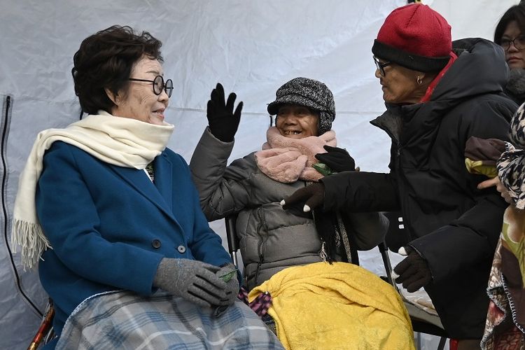 Mantan wanita penghibur Lee Yong-soo (kiri) dari Korea Selatan dan Narcisa Claveria (tengah) dan Estelita Dy (kanan) dari Filipina, yang dipaksa menjadi budak seks bagi pasukan Jepang selama Perang Dunia II, saling menyapa ketika mereka berpartisipasi dalam demonstrasi mingguan menuntut permintaan maaf resmi pemerintah Jepang, di dekat kedutaan besar Jepang di Seoul pada 20 November 2019.