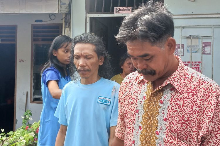 Henderson Harianja (49) (kiri) dan didampingi Ketua RT Anggiat Situmorang berjalan keluar dari kediamannya menuju mobil Kemensos sebelum berangkat ke RSJ di Jalan Pisang, Gang Delima RT/03/RW 09, Kelurahan Pardamean, Kecamatan Siantar Marihat, Kota Pematangsiantar, Sumatera Utara, Selasa (5/11/2024).