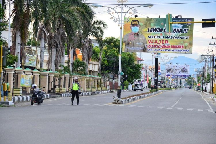 Seorang aparat kepolisian berjaga di ruas jalan utama Kota Gorontalo saat penerapan PSBB. Kelanjutan PSBB akan dibahas besok dan diumumkan Senin