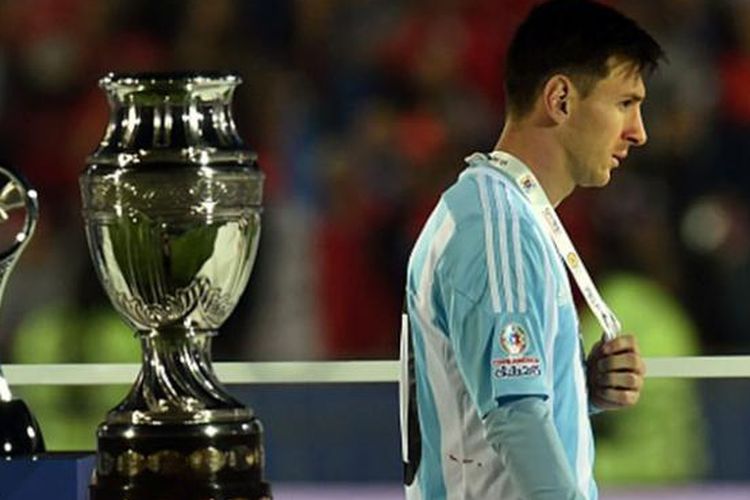 Lionel Messi berjalan melewati trofi Copa America tanpa mau melihatnya saat prosesi pengalungan medali kepada timnas Argentina usai final edisi 2015 di Santiago, Chile. 