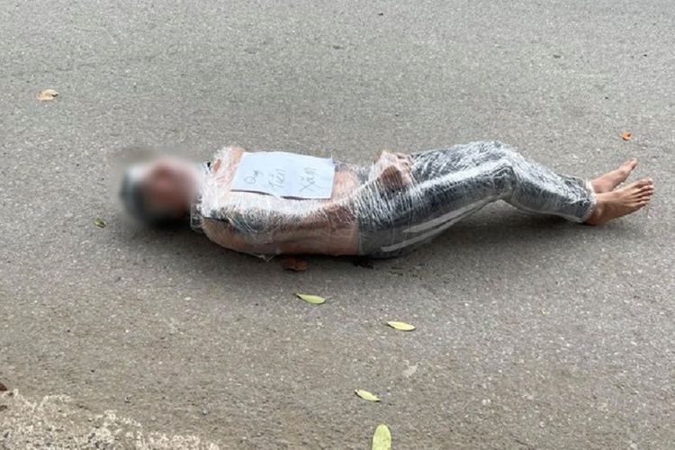 Gambar yang menyebar di media sosial di Vietnam memerlihatkan seorang pria dibungkus plastik dalam keadaan setengah jalan. Pria itu kemudian diikat di pohon sebagai hukuman karena tak membayar biaya pembuatan tato di tangannya.