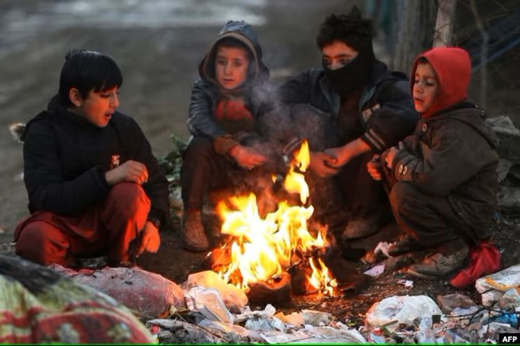 Sejumlah laki-laki Afghanistan duduk di dekat api unggun di sepanjang jalan, pada musim dingin di Kabul pada 30 Desember 2022.