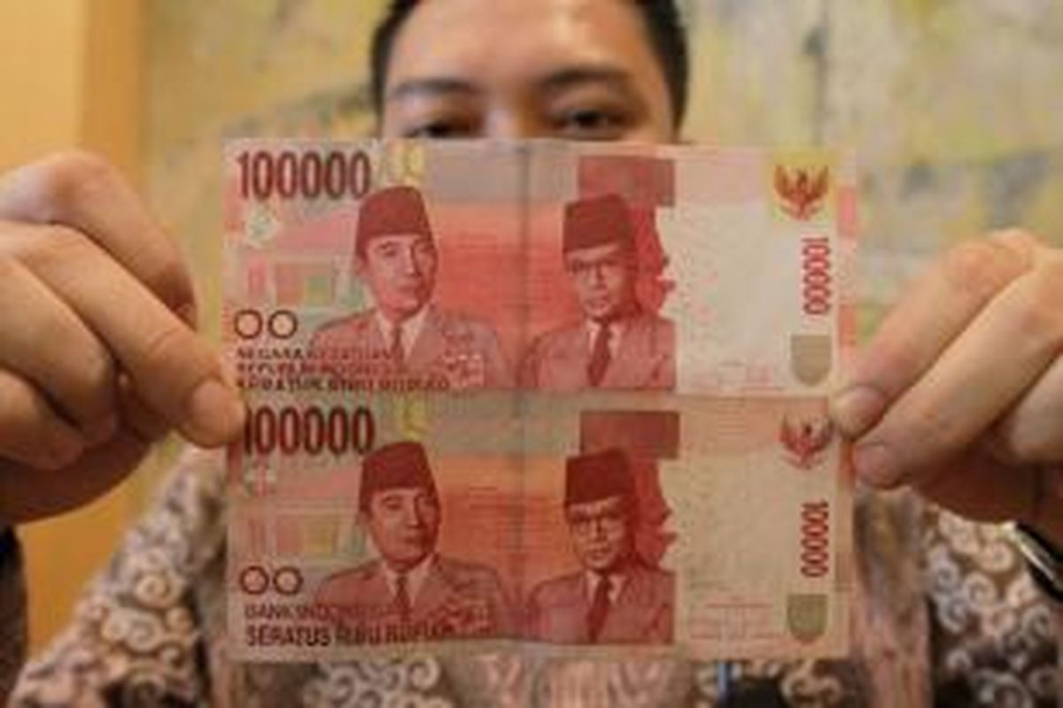 Karyawan menunjukkan uang pecahan Rp 100 ribu baru (atas) dan yang lama, usai peluncuran uang NKRI tahun emisi 2014 di kantor Bank Indonesia, Jakarta Pusat, Senin (18/8/2014). Bank Indonesia bersama Pemerintah Republik Indonesia mengeluarkan dan mengedarkan Uang Rupiah Kertas Pecahan Rp. 100.000 Tahun Emisi 2014 yang bertepatan dengan Hari Ulang Tahun ke-69 Kemerdekaan Republik Indonesia.