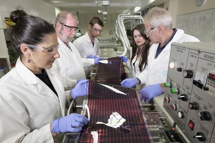 Para ilmuan di CSIRO sedang memegang prototipe panel surya yang bisa dicetak