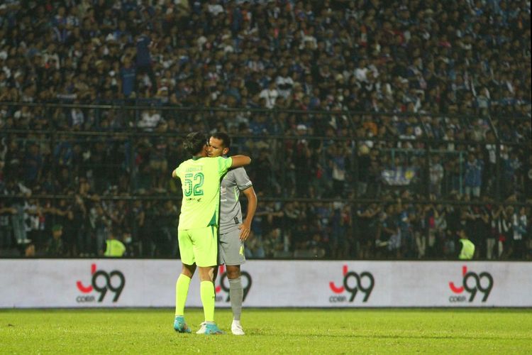 Kiper pengganti Persebaya Surabaya, Andhika Ramadhani, memeluk bek Leo Lelis pada laga Liga 1 2022-2023 Arema FC vs Persebaya di Stadion Kanjuruhan, Kab Malang, pada Sabtu (1/10/2022).