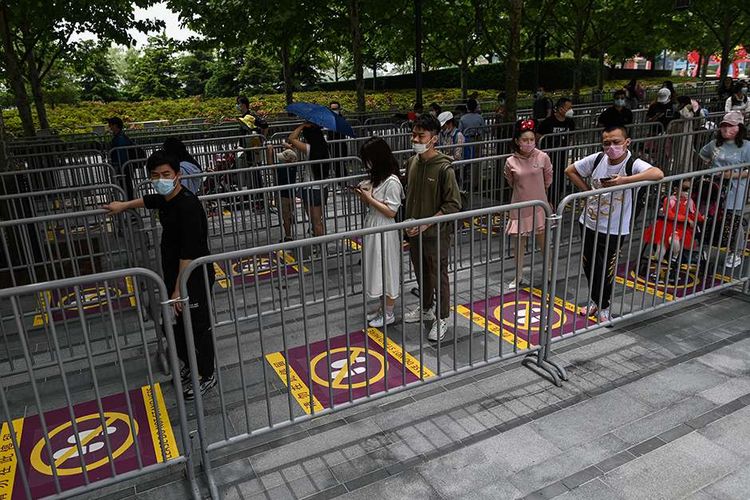 Pengunjung mengenakan masker, mengantre dengan aturan pembatasan jarak (physical distancing) saat hendak masuk ke taman hiburan Disneyland, Shanghai, China, yang baru dibuka kembali, Senin (11/5/2020). Shanghai Disneyland resmi kembali dibuka setelah ditutup selama 4 bulan akibat pandemi virus corona.