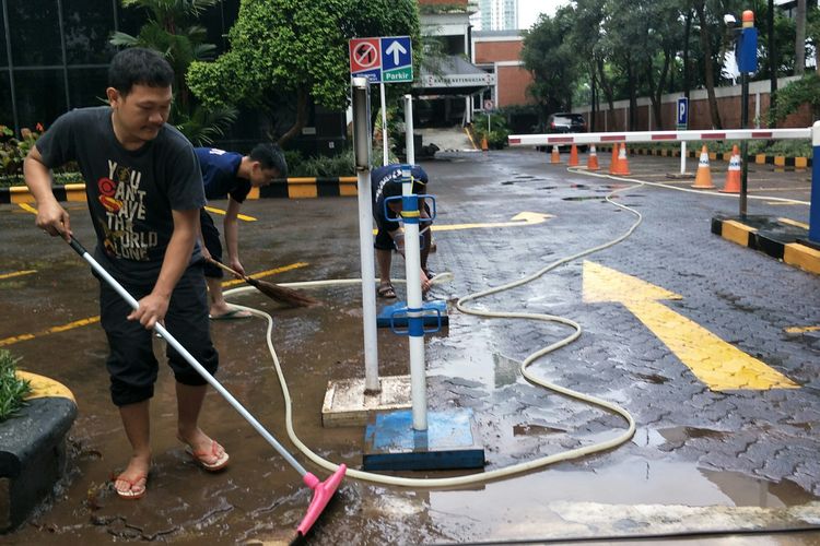 Petugas sekuriti Graha Arda membersihkan halaman gedung yang sempat terkena banjir Jalan Jalan HR Rasuna Said, Jakarta Selatan, Minggu (23/2/2020).