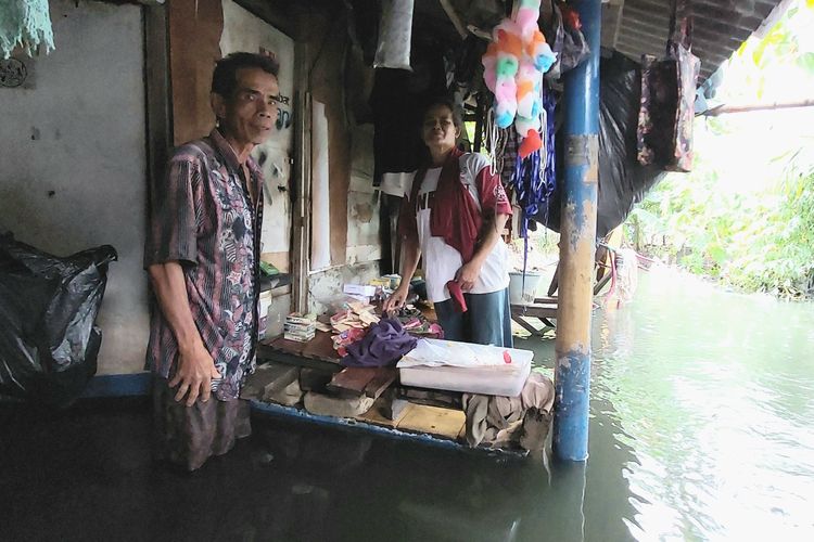 Sepasang lansia  di RT 15 RW 03, Tegal Alur, Kalideres, Jakarta Barat, terpaksa tidak mengevakuasi diri dari banjir demi melindungi gerobak dagangan aksesoris berharganya, Kamis (20/1/2022).