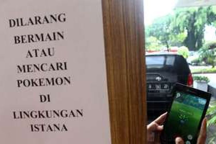 Seorang pria membuka game virtual Pokemon Go di samping kertas larangan, di lingkungan Istana Negara, Jakarta, Rabu (20/7/2016). Larangan bermain Pokemon Go di area Istana Kepresidenan yang merupakan objek vital negara diterapkan untuk menjaga keamanan.