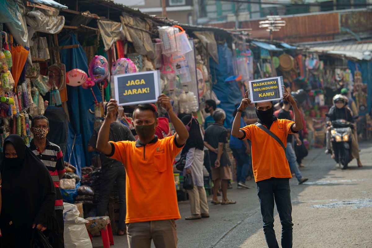 Petugas pengelola pasar melakukan sosialisasi pencegahan COVID-19 dengan membawa poster berisi pesan di Pasar Jatinegara, Jakarta, Kamis (11/6/2020). Upaya tersebut untuk meminimalisir kasus penularan atau penyebaran COVID-19 terjadi di pasar.