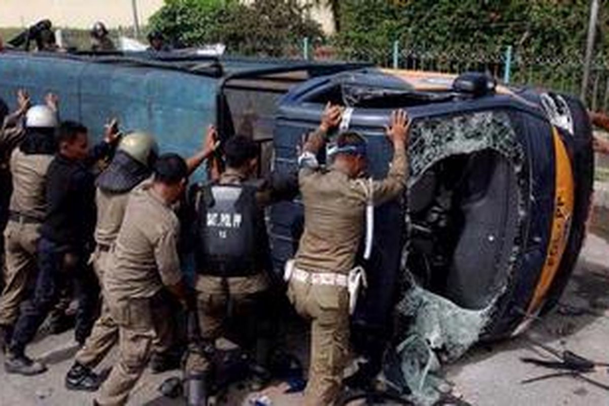 Anggota Satpol PP mengevakuasi mobil yang dirusak massa saat bentrok antara warga dengan Satpol PP dalam upaya pembongkaran kompleks makam Mbah Priuk di Koja, Jakarta Utara, Rabu (14/4/2010). 