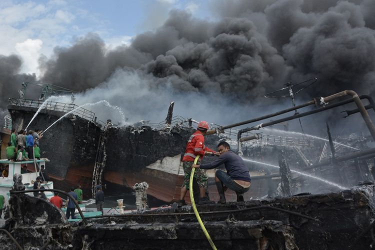 Petugas pemadam kebakaran dan warga berusaha memadamkan api yang membakar kapal ikan di Pelabuhan Benoa, Denpasar, Bali, Senin (9/7). Sekitar 39 unit kapal ikan terbakar dalam peristiwa kebakaran yang terjadi sejak pukul 02.00 Wita tersebut. 