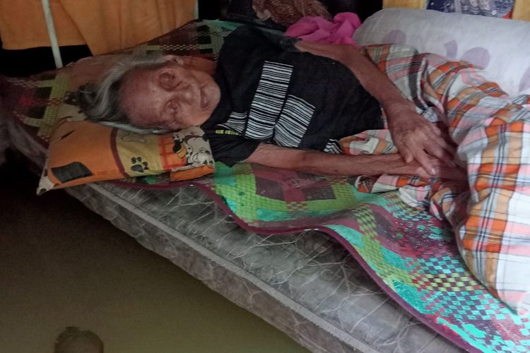 Nuriah (90) tahun terpaksa tidur di atas kasur yang bawahnya tergenang air banjir di wilayah Legok, Kota Jambi, pada Sabtu (20/1/2024).