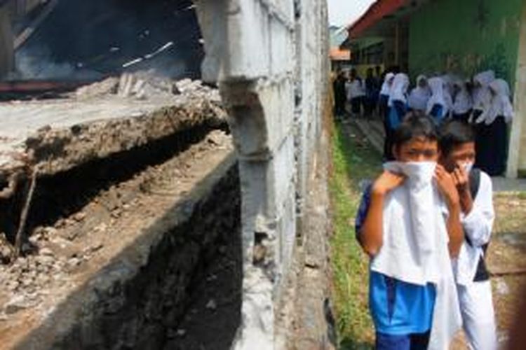 Siswa SMP PGRI Plumbon Kabupaten Cirebon melintas di tembok yang jebol, asap yang masuk sekolah dan mengganggu aktivitas belajar mengajar, Jumat Siang (19/9/2014)