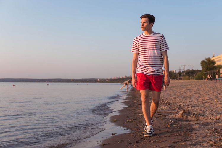 Ilustrasi laki-laki memakai baju merah di pantai.