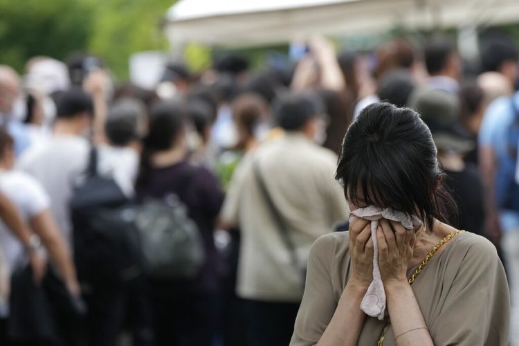 Salah satu orang yang mempersembahkan bunga dan doa untuk mantan Perdana Menteri Shinzo Abe, menangis di kuil Zojoji sebelum pemakamannya di bangun Selasa, 12 Juli 2022, di Tokyo.