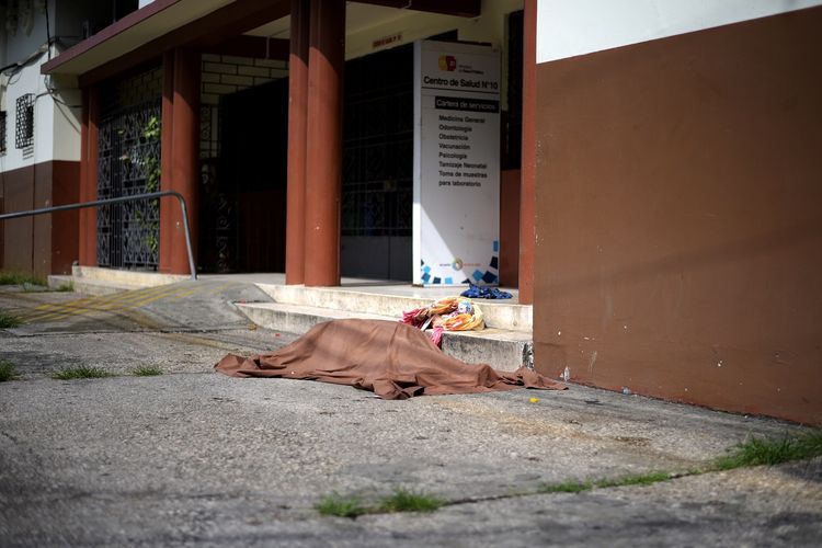 Sebuah jenazah yang tertutupi kain tergeletak di luar Kementerian Kesehatan Publik Ekuador, di tengah wabah virus corona, pada 4 April 2020.