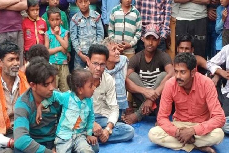 Santosh Kumar duduk memangku anaknya yang berusia tiga tahun saat berjudi dengan Ram Bhajan Sah (baju merah). 