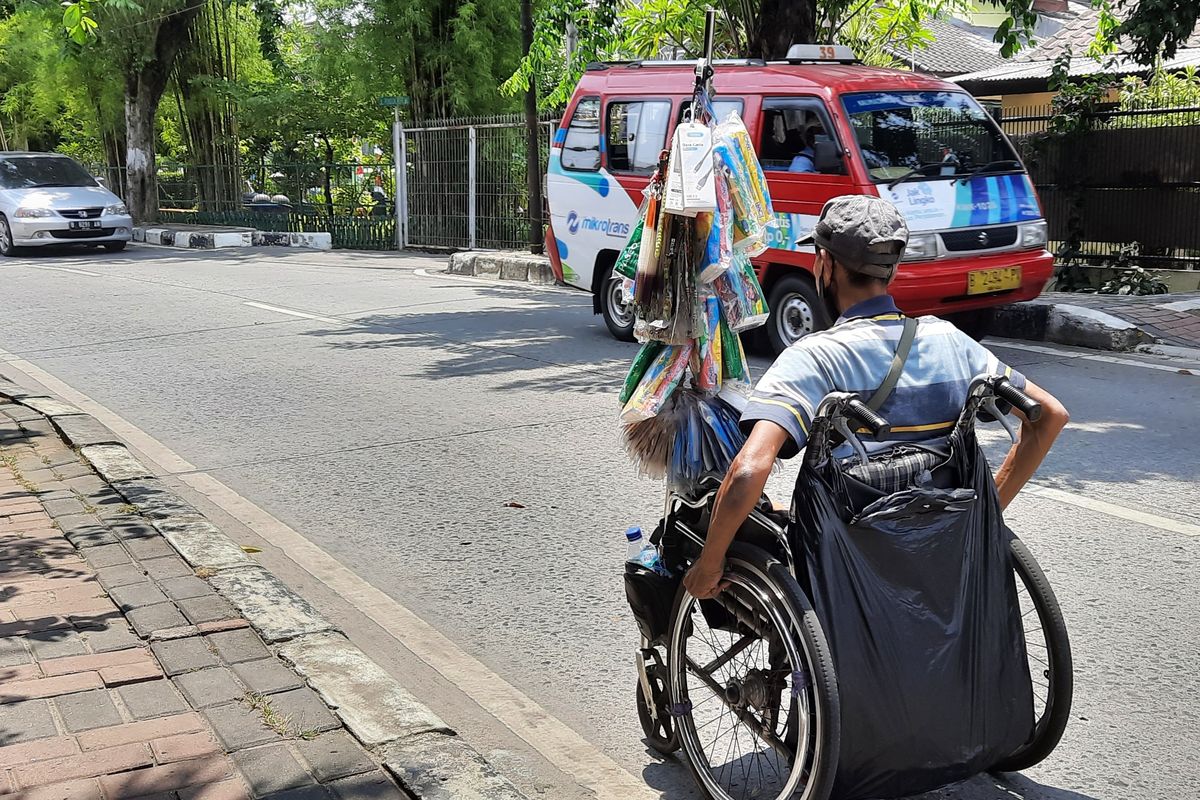 Di tengah keterbatasannya, Abit tetap semangat berjualan menggunakan kursi roda, aktivitas sehari-hari yang ia lakoni sejak 1984. Foto diambil di Pos Polisi Pondok Kopi, Duren Sawit, Jakarta Timur.