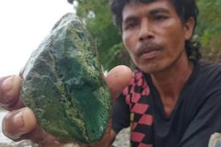Pencari bongkahan batu akik menunjukan material dasar batu akik jenis badar lumut yang ditemukan di Sungai Klawing, Purbalingga, Jateng. 
