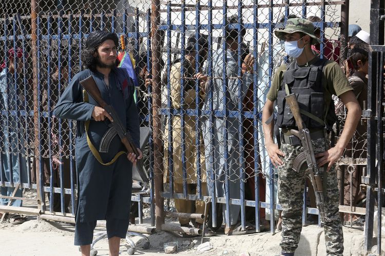 Paramiliter Pakistan (kanan) dan anggota Taliban (kiri) saat di titik penyeberangan antara Pakistan dan Afghanistan di Torkham, Pakistan, 21 Agustus 2021.