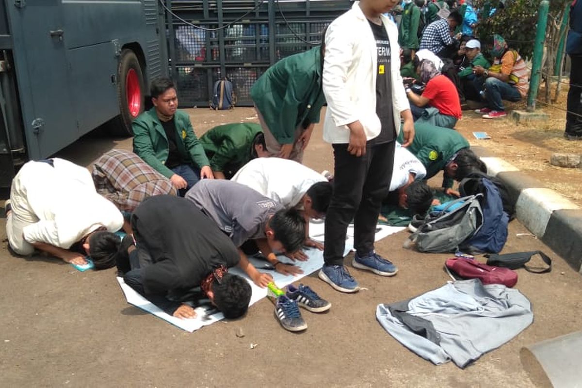 Sejumlah mahasiswa melaksanakan sholat dzuhur berjamaah di depan Gedung DPR RI, Jalan Gatot Subroto, Selasa (24/9/2019). 