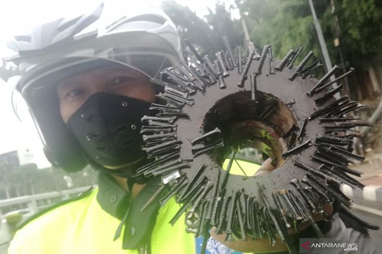 Relawan Sapu Bersih (Saber) Abdul Rohim melakukan penyapuan dengan magnet saat razia ranjau paku di Jalan Gatot Subroto, Jakarta Selatan