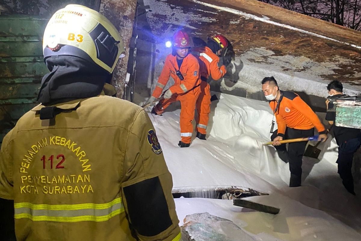 Petugas gabungan saat melakukan evakuasi dump truk yang terperosok menimpa rumah di Surabaya, Minggu (9/7/2023).