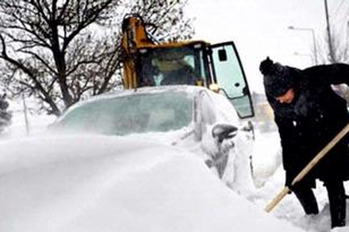 Seorang perempuan mencoba membersihkan mobilnya dari salju yang semakin tebal menimbun kawasan pedesaan Catelu, di tenggara Bucharest. 