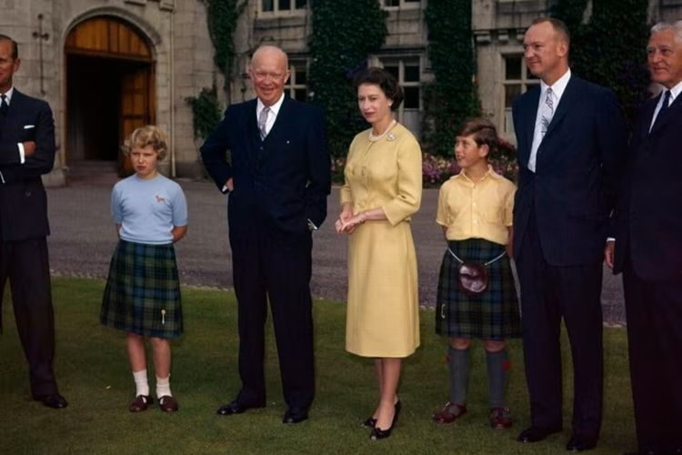 Ratu Inggris Elizabeth II berdiri di atas tanah Kastil Balmoral, di Royal Deeside, Skotlandia, antara Presiden AS Dwight D. Eisenhower dan Pangeran Charles, 29 Agustus 1959.