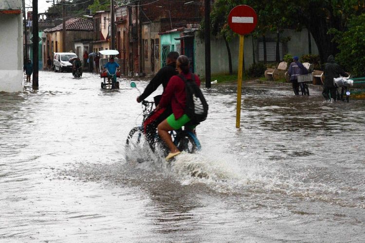 Dalam foto yang dirilis ACN ini, tampak warga mengendarai sepeda motor di jalan setelah hujan lebat menyebabkan banjir di Camaguey, Kuba pada Jumat (9/6/2023). Hujan deras beberapa hari terakhir menyebabkan banjir di berbagai provinsi di Kuba tengah dan timur, dengan kematian satu orang, ribuan pengungsi, dan banyak kerusakan material.