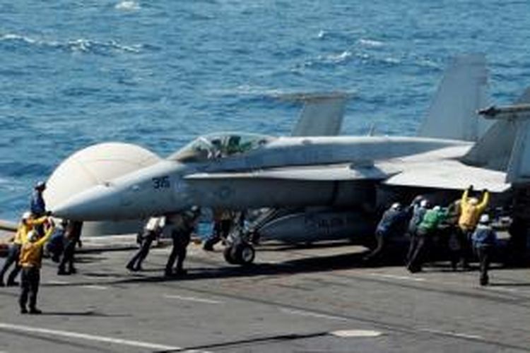 Petugas memandu pesawat F/A-18C Hornet di dek Kapal Induk USS George HW Bush milik US Navy di Teluk Persia, Minggu (10/8/2014).