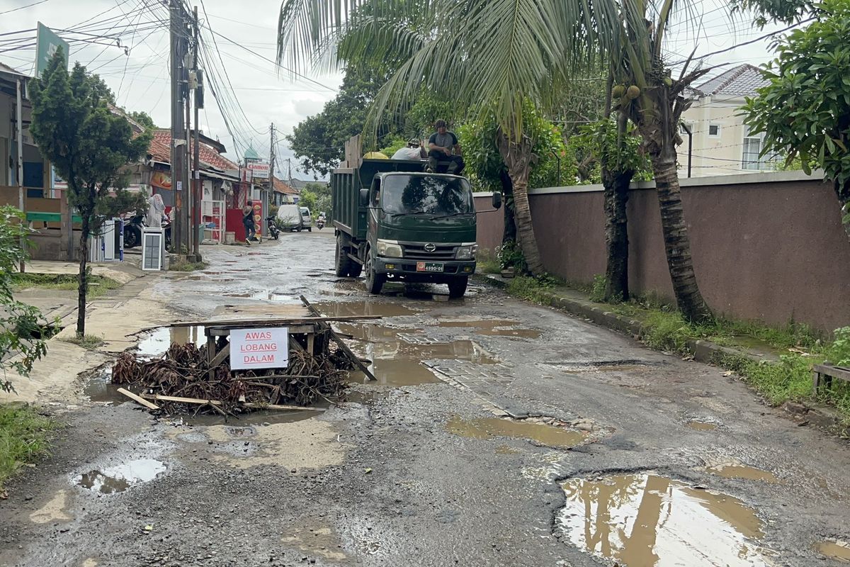 Kondisi jalan yang rusak hingga dipasang meja penanda di Jalan Mampang Indah I, perbatasan wilayah Mampang dan Grogol, Kota Depok, Kamis (18/12/2025).