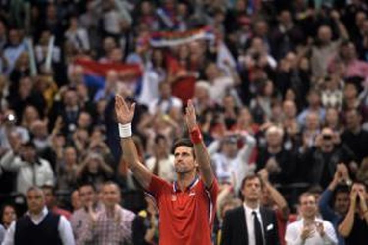 Petenis Serbia,  Novak Djokovic merayakan kemenangannya atas petenis Ceko, Tomas Berdych pada laga keempat final Davis Cup 2013 di Belgrade Arena, Minggu (17/11/2013).