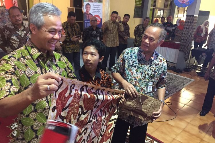 Gubernur Jawa Tengah Ganjar Pranowo mengamati kain batik pada peringatan Hari Batik di Banyumas, Senin (2/10/2017). Ganjar mengaku sering mempromosikan batik Jawa Tengah ke berbagai kegiatan dengan mengenakan batik dan memamerkannya.