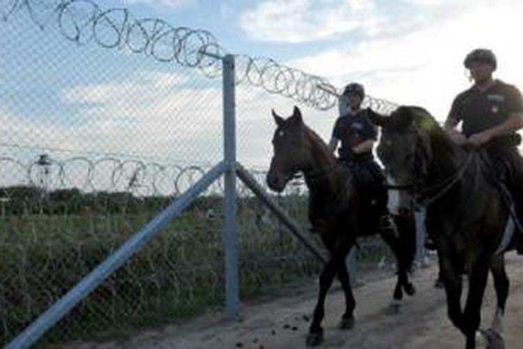 Polisi berkuda Hungaria berjaga di pagar yang baru dibangun untuk menangani pengungsi 