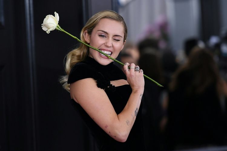 Miley Cyrus membawa setangkai mawar putih ketika menghadiri Grammy Awards 2018 di Madison Square Garden, New York, MInggu (28/1/2018).