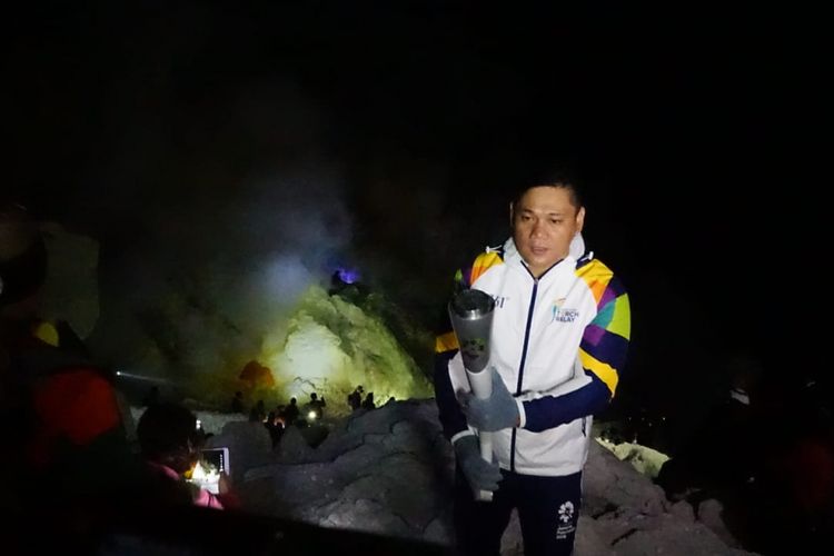 Pino, mantan atlet tinju dengan membawa obor Asean Games berdiri pinggir kawah berlatar belakang api biru gunung Ijen Minggu (22/7/2018)