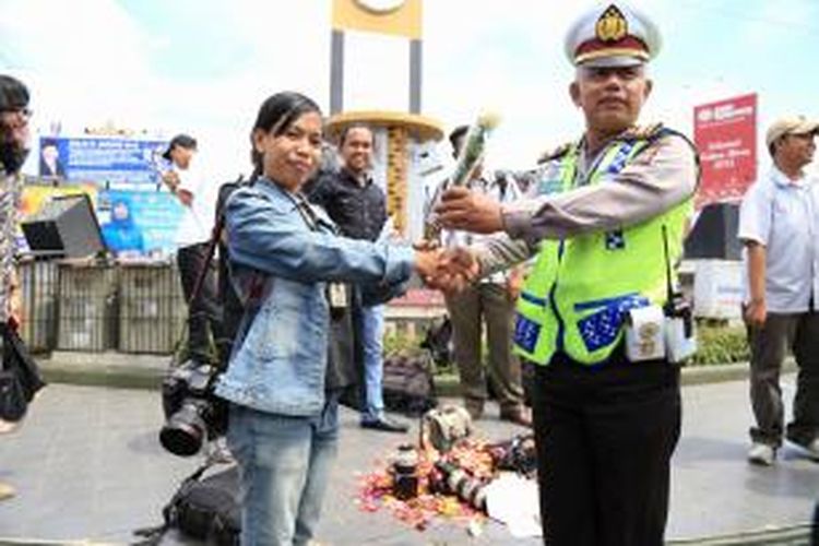 Seorang wartawati memberikan bunga kepada polisi saat aksi solidaritas jurnalis di Bundaran Adipura Bandar Lampung, Kamis (5/3)