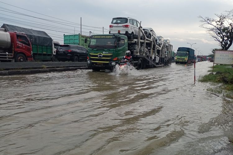 Kendaraan berjalan pelan-pelan saat melintasi genangan air rob di Jalur Pantura Desa Sidogemah Kecamatan Sayung Kabupaten Demak Jawa Tengah, Minggu (22/5/2022)
