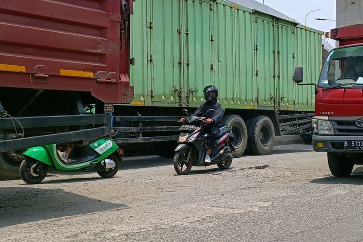 Ilustrasi berkendara di antara truk besar.