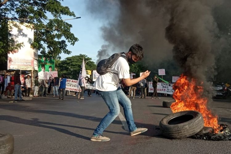 Seorang pengunjuk rasa tolak omnibus law saat berada di dekat ban yang terbakar di Jalan Sultan Alauddin Makassar, Rabu (28/10/2020).