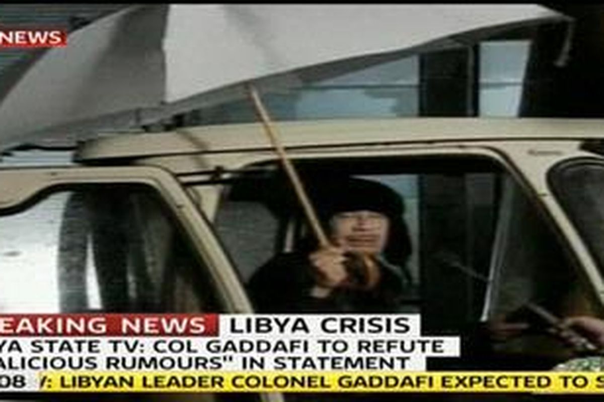 Khadafy memberikan pernyataan singkat di televisi Libya, Senin (21/2/2011) malam. Ia tampak memegang payung,  duduk di kursi bagian depan sebuah van, dan menegaskan dirinya tidak kabur dari negara itu.