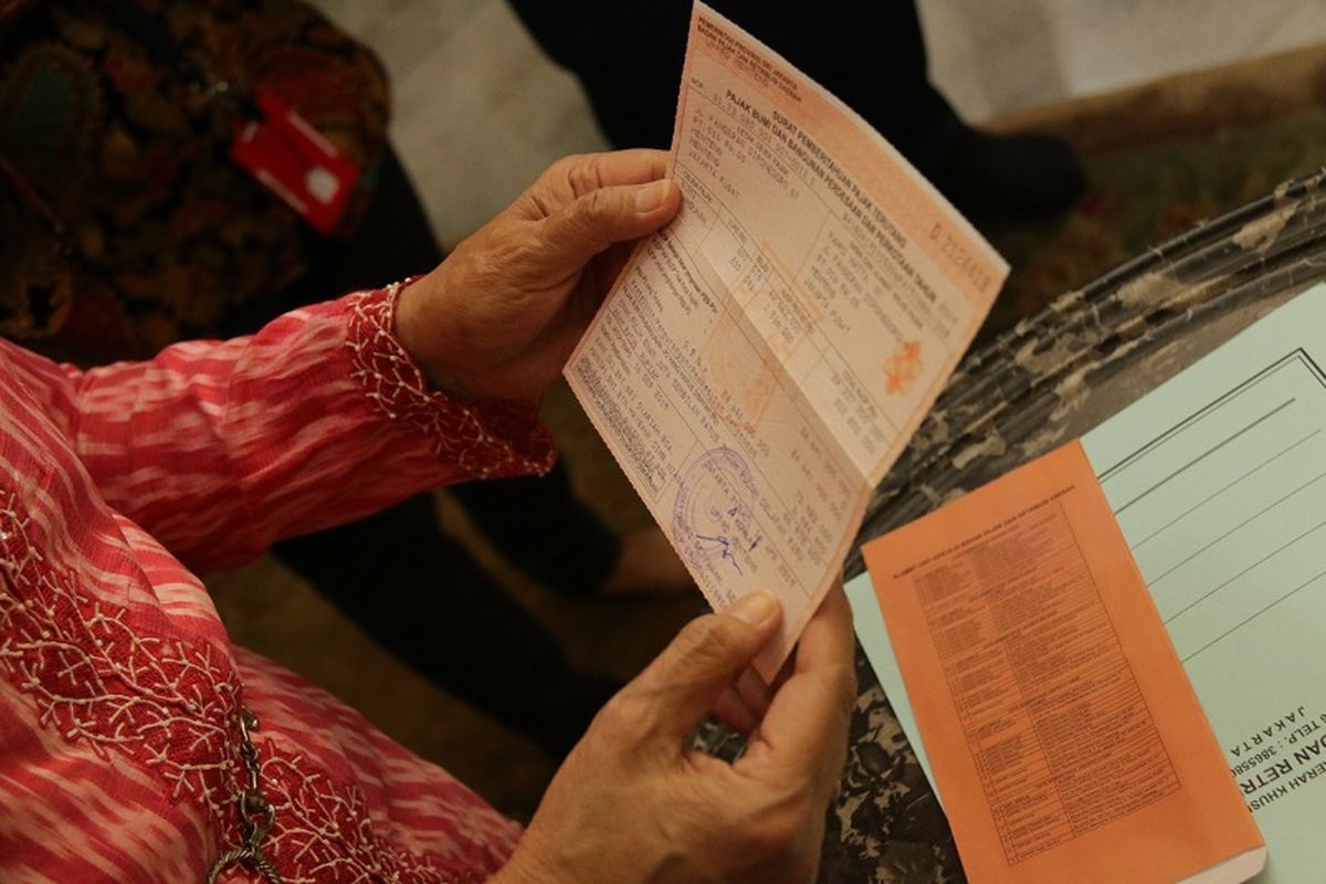 Seseorang sedang menunjukkan tagihan Pajak dan Bumi (PBB) yang harus ia bayar.